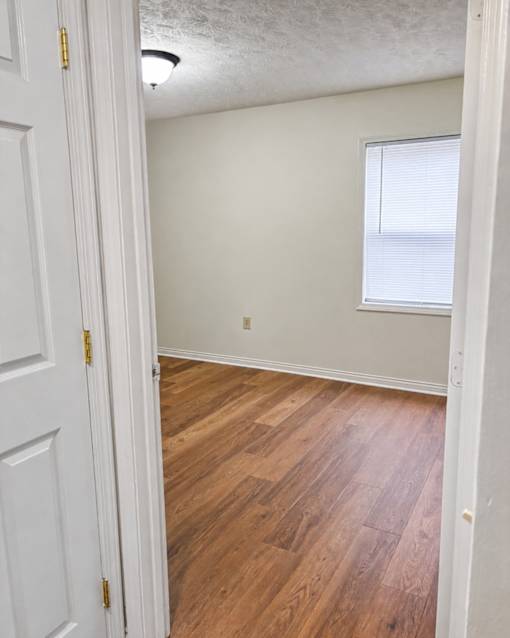 A room with a white door and wooden flooring.