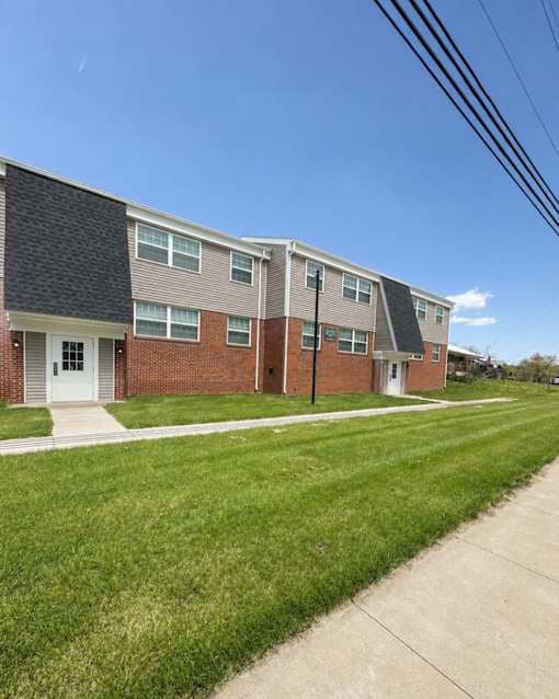 A row of townhouses with a sidewalk in front.