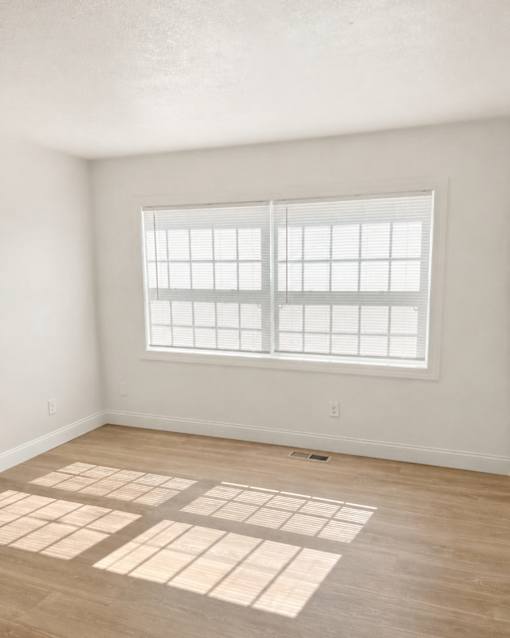 A room with a window and wooden flooring.