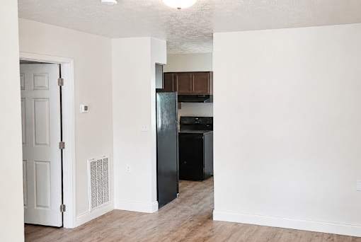 A kitchen area with a black fridge and wooden floors.