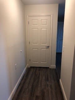 A white door is in a hallway with wood flooring.