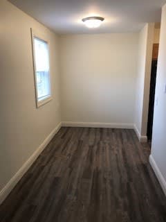 A room with a window and a wooden floor.