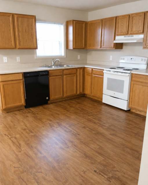 A kitchen with wooden cabinets and a black dishwasher.