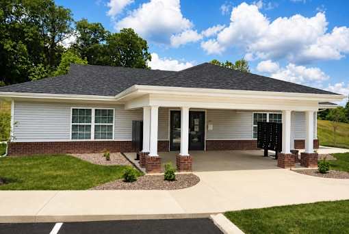A small white building with a black roof and a covered porch.