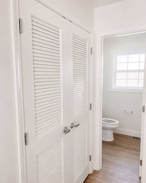 A white bathroom with a toilet and a window.