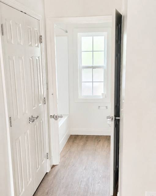 A white door is open to a hallway with a window.