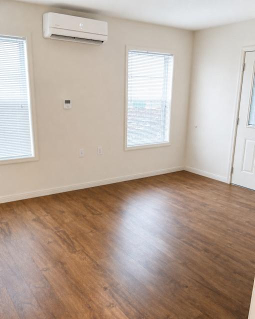 A room with wooden floors and two windows.