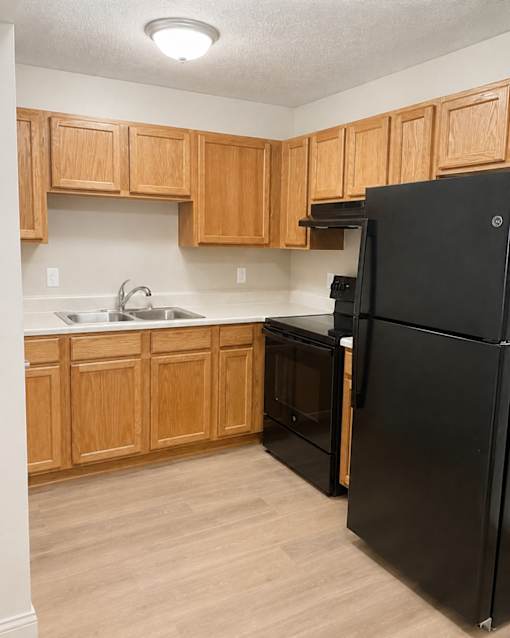 A kitchen with wooden cabinets and a black refrigerator.