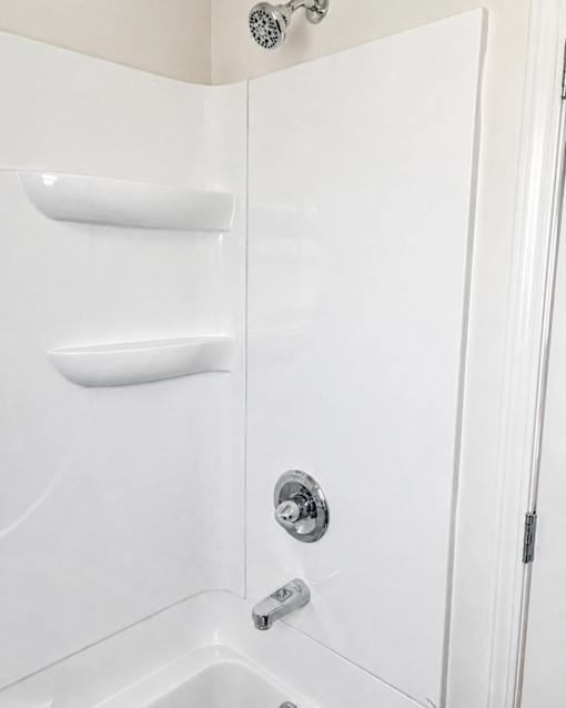 A white shower stall with a door and a shower head.