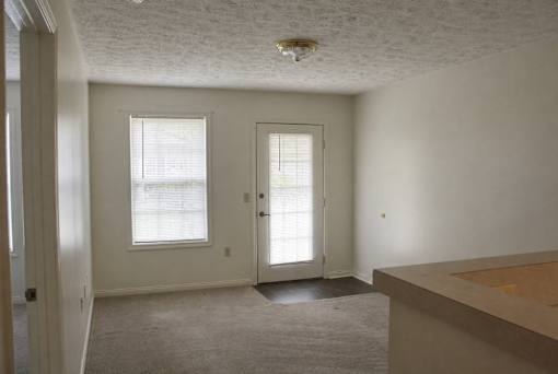 A room with a carpeted floor and a window with blinds.