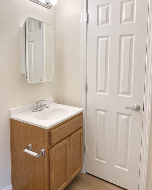 A white bathroom sink with a wooden cabinet and a white door.