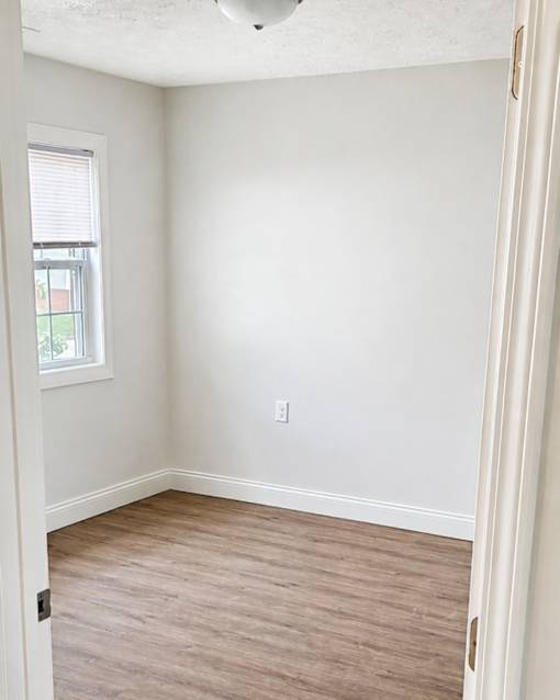 A room with a window and a light switch on the wall.
