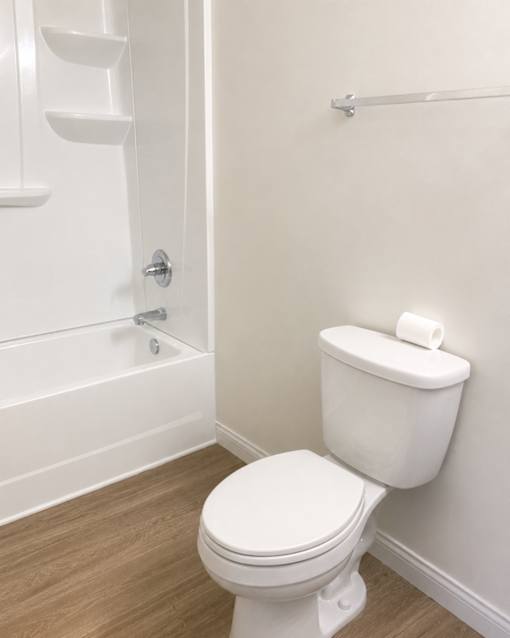 A white toilet with a toilet paper roll on top of it.