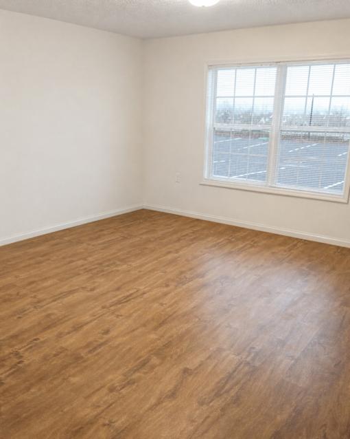 A room with a window and wooden flooring.