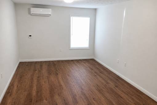 A room with wooden flooring and a window.
