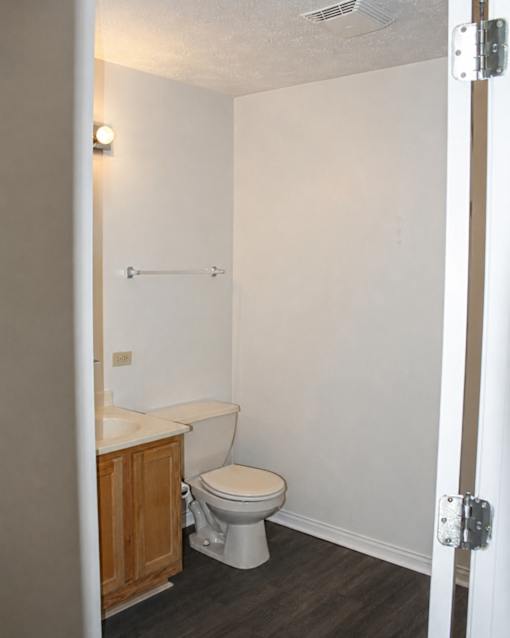 A white toilet in a small bathroom with a wooden cabinet.