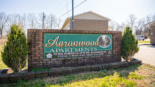 A sign for Harwood Apartments is displayed in front of a building.