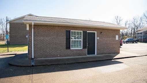 A small brick building with a black door and a white window.