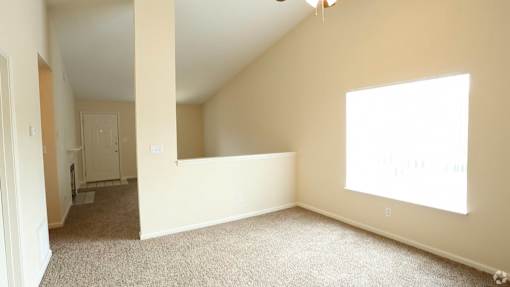 A room with a carpeted floor and a window letting in sunlight.