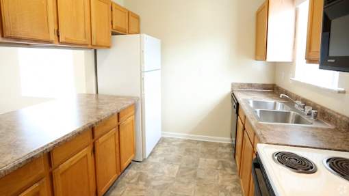 A kitchen with brown cabinets and a white fridge.