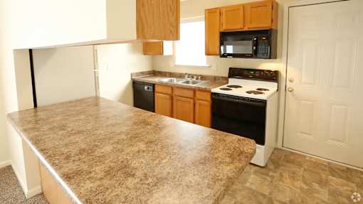 A kitchen with a granite countertop and wooden cabinets.