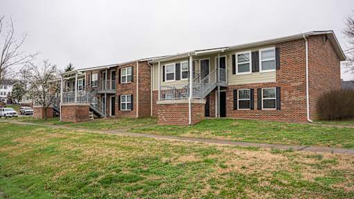 A row of red brick apartment buildings with green grass in front.