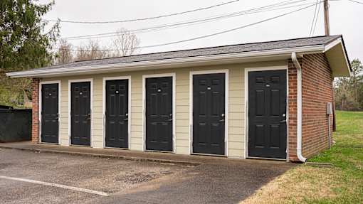 A building with four black doors and a brick chimney.