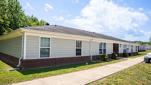 A small house with a grey roof and a white car parked in front.