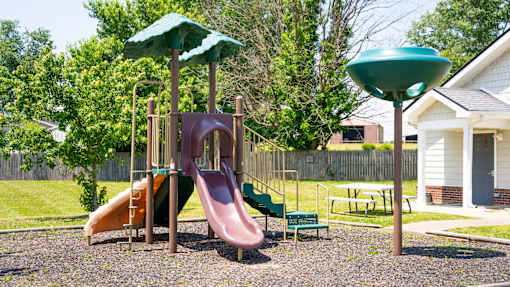 A playground with a slide, swings, and a green canopy.
