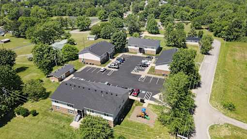 An aerial view of a parking lot and buildings surrounded by trees.