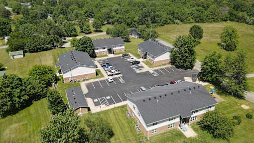 An aerial view of a building surrounded by a parking lot and trees.