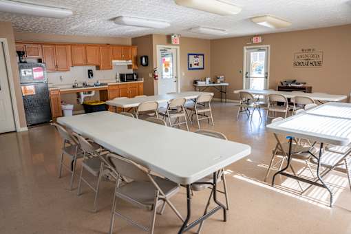 A room with tables and chairs and a sign that says Bowling Green School House.