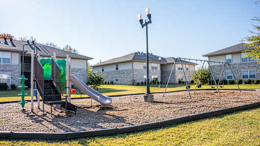 A playground with a green slide and a black pole.