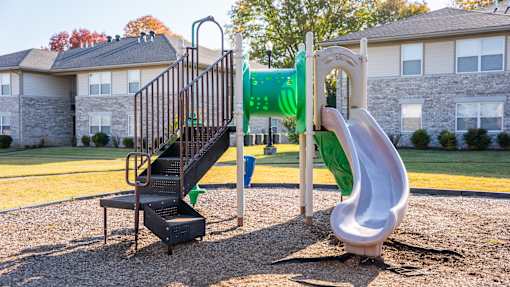 A playground with a green slide and a white slide.