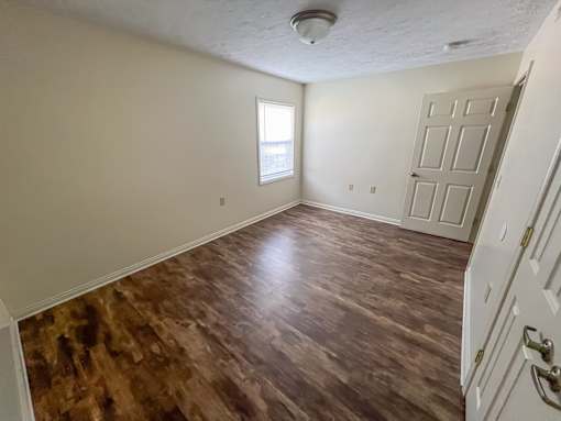 A room with a wooden floor and a white door.