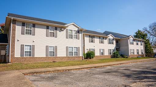 Apartment building with a parking lot in front.
