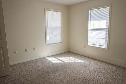 A room with two windows and carpeted floor.