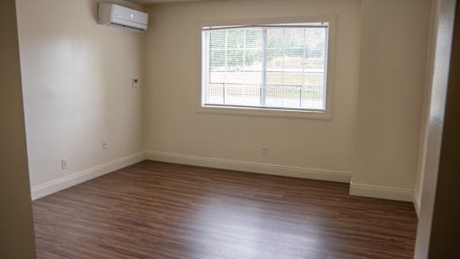 A room with a window and wooden flooring.