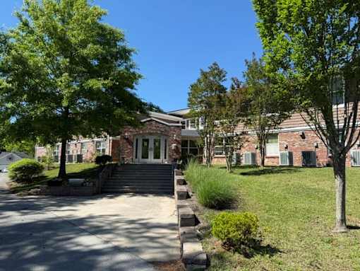 A building with a brick facade and a green lawn in front.
