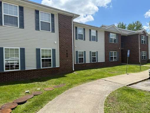 A building with a brick facade and a grassy area in front.