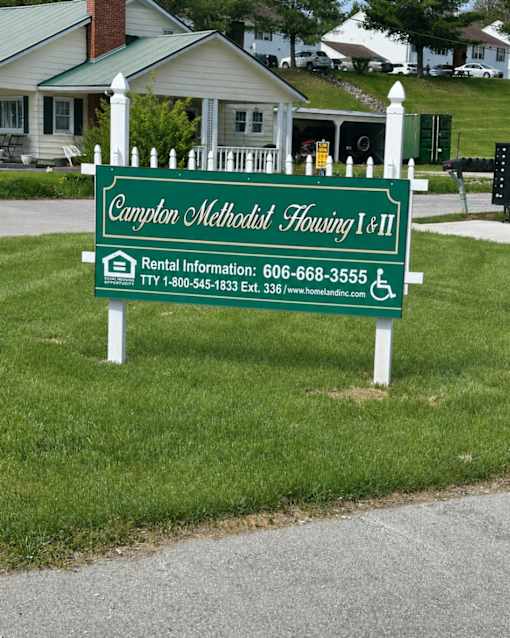 A sign for Campton Methodist Housing I & II is in front of a house.