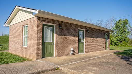 A small brick building with a green door and windows.