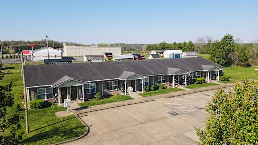 A large building with a grey roof and a parking lot in front.