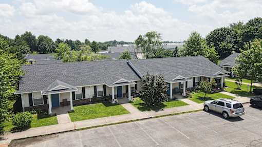 A building with a grey roof and a parking lot in front.