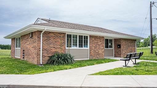 A small brick house with a grey roof and a small porch.