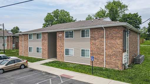 A brick apartment building with a car parked in front.