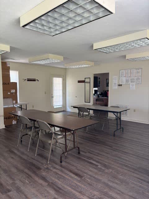 A room with a long table and chairs, and boxes on the floor.