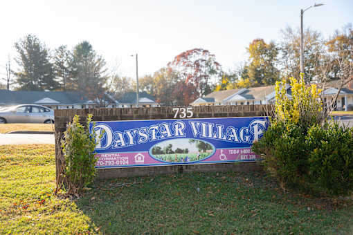 A sign for Daystar Village with a phone number on it.