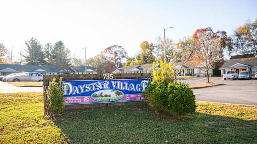 A sign for Daystar Village stands in front of a grassy area.