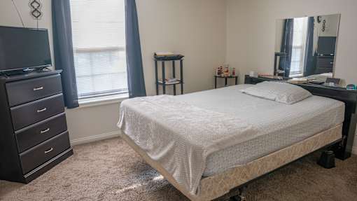 A bedroom with a bed, dresser, and mirror.